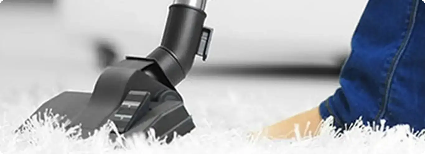 Close-up of a professional vacuuming a white carpet in Irving.